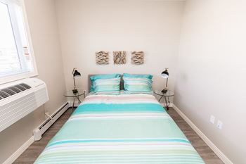 A bedroom with a bed, two lamps, and a window.